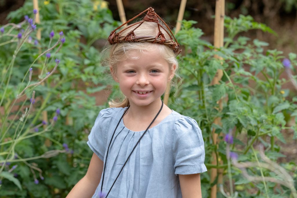 Smiling child wearing a wicker crown.