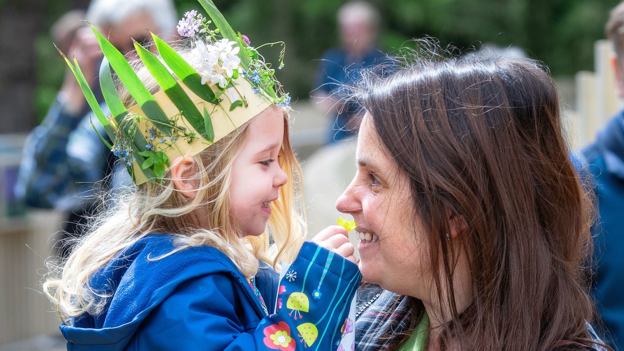 A child wearing a crown made of flowers and leaves.