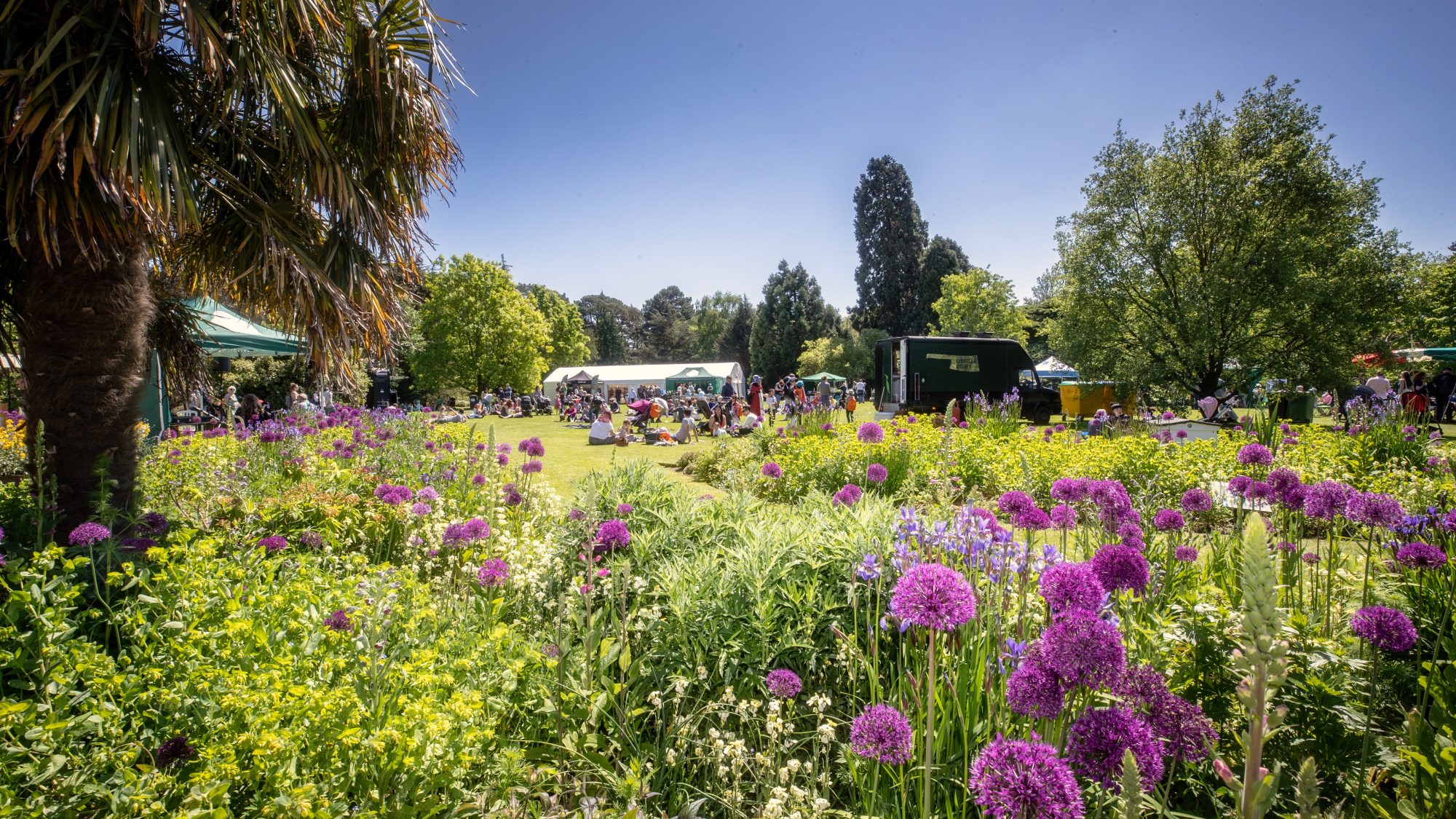 A view over the bee borders of the main lawn with food trucks, tents and visitors.