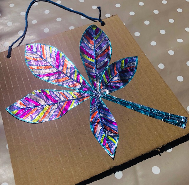 A leaf shape is cut out from tin foil and coloured in with different pinks and oranges.