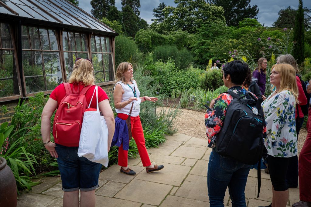 A woman speaks to a tour group outside of the glasshouse range.