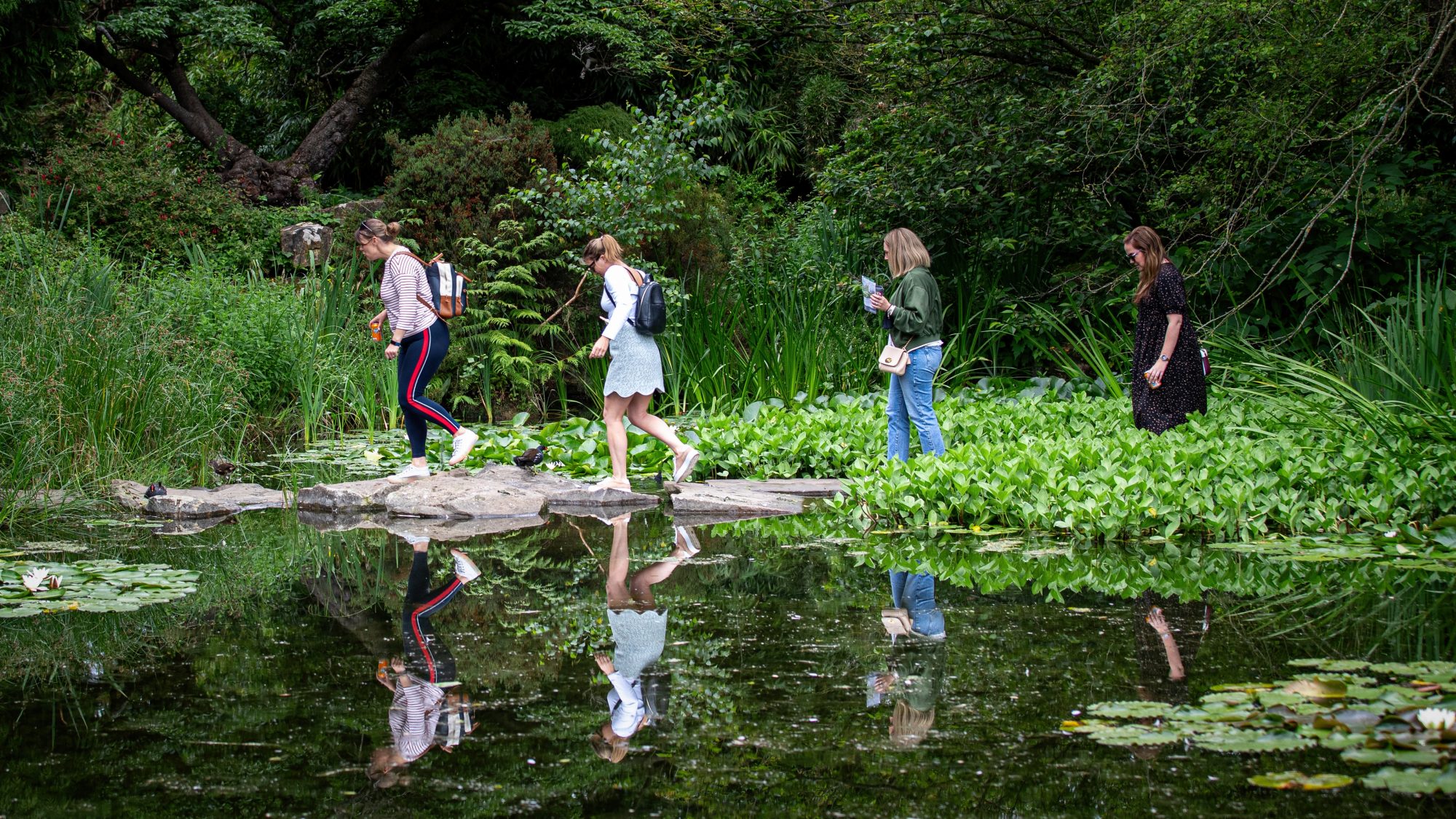 visitors walking across the stepping stones on the lake