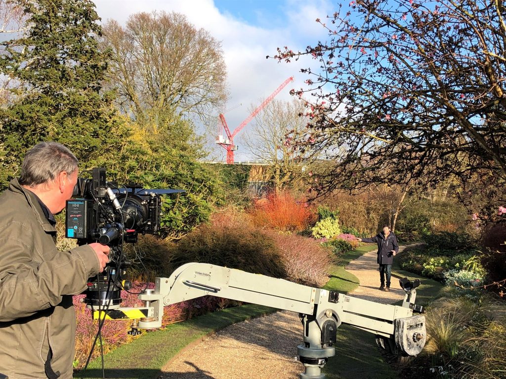 A film crew recording a man on the path in the Winter Garden.