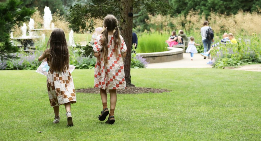Children heading towards the Garden's fountain with a trail map