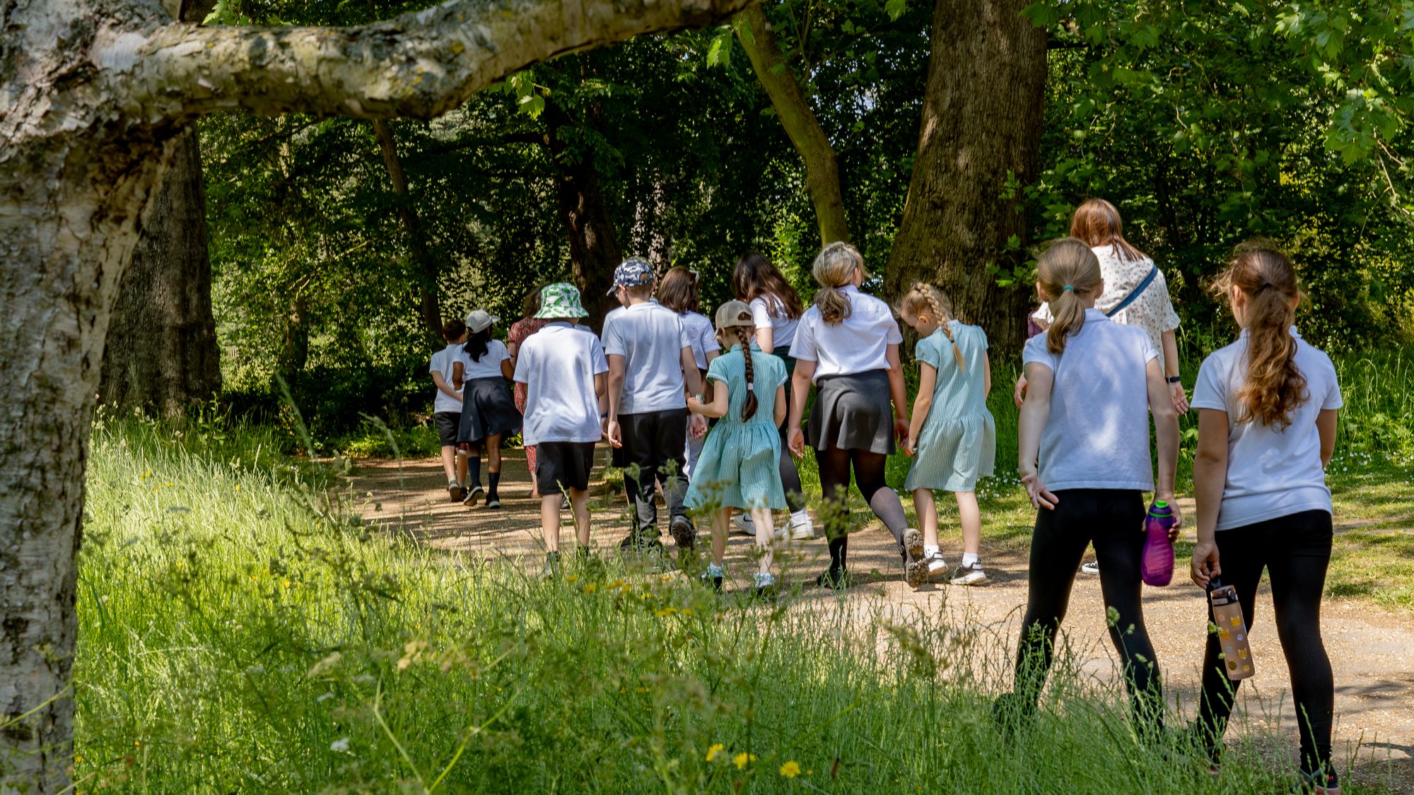 A group of school children walk down a path in the sun