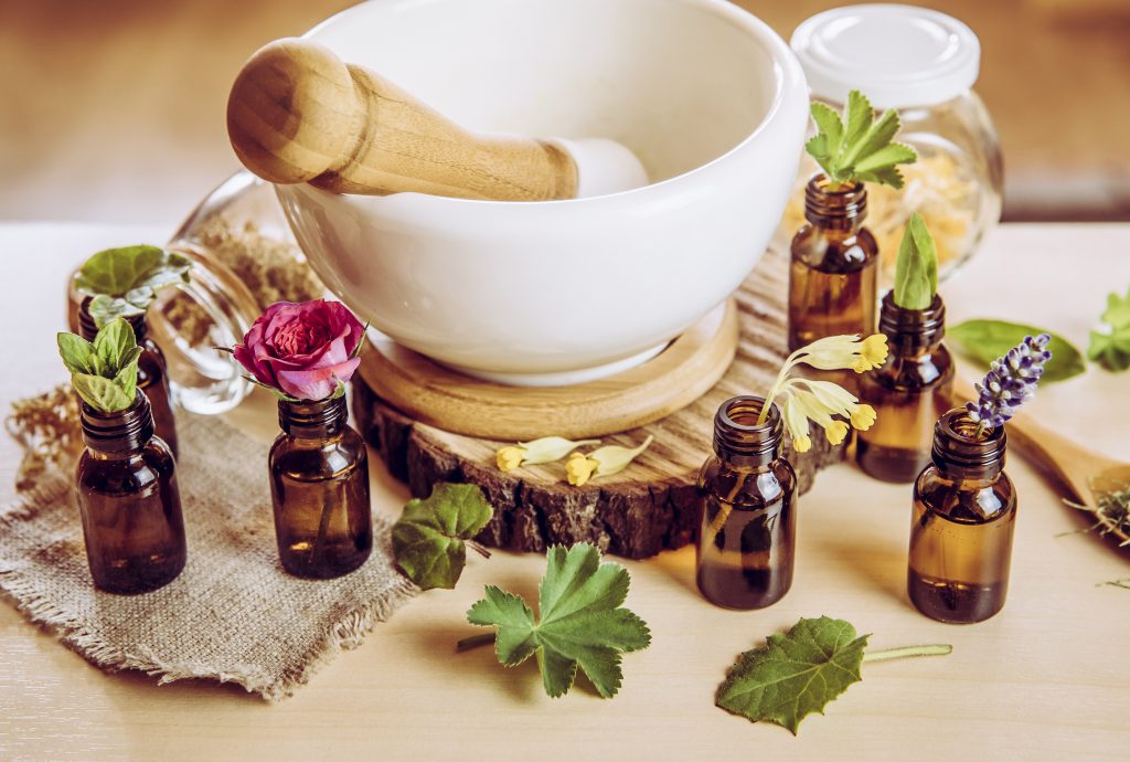 a pestle and mortar with plant material and small brown bottles