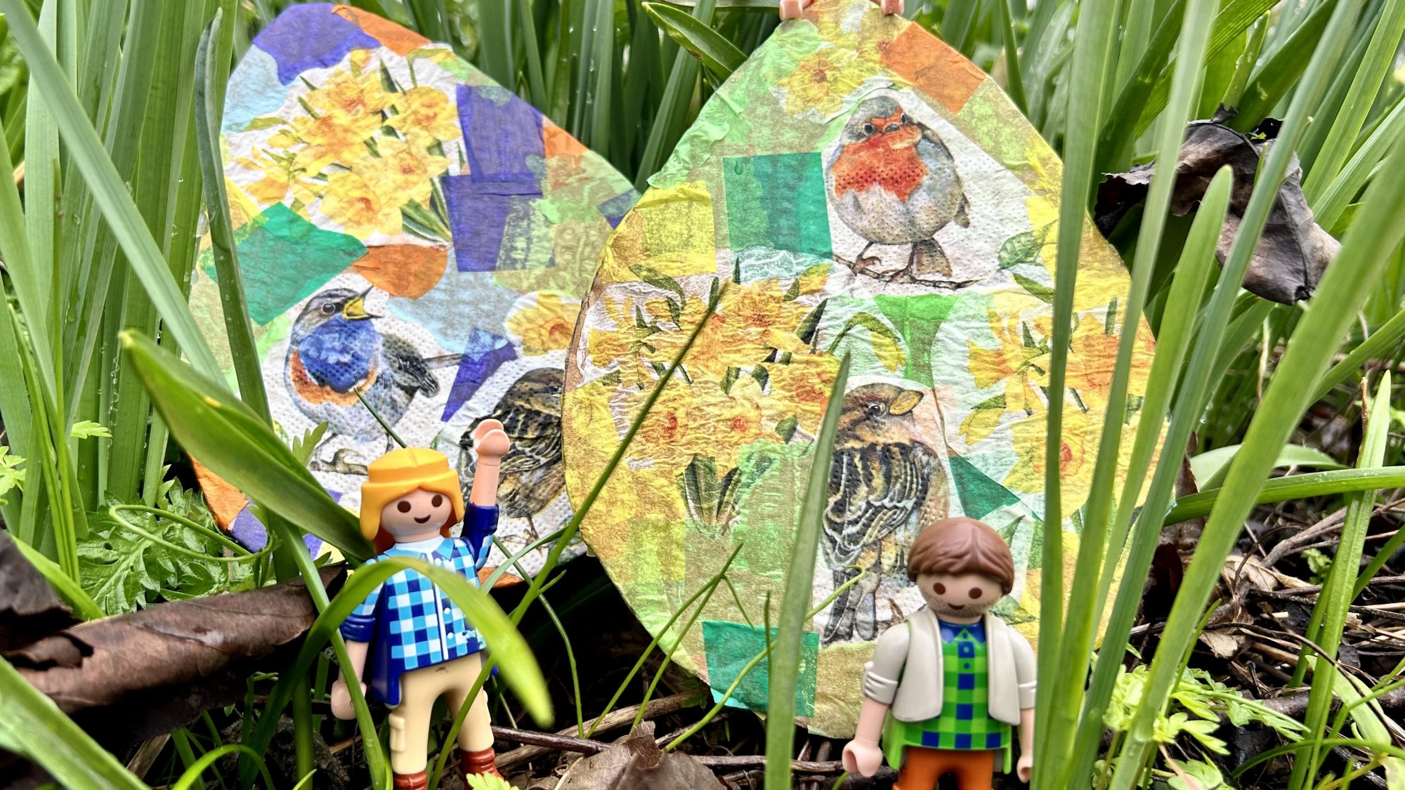 Image showing two decoupaged cardboard Easter egg shapes amongst plants