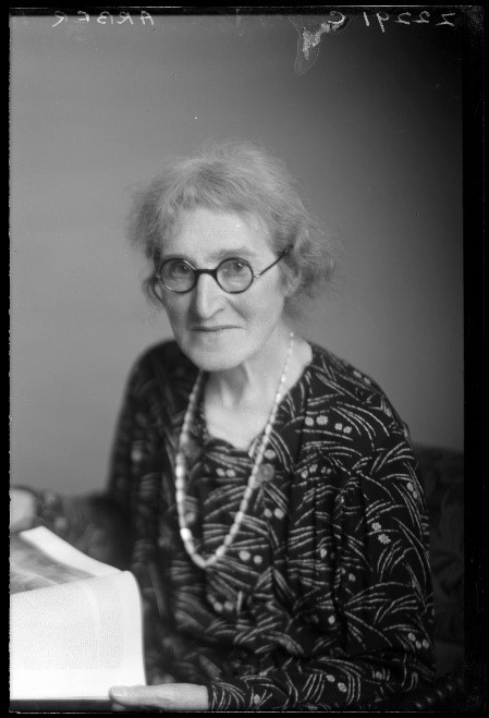 A black and white photograph of Agnes Arber as an old woman with glasses and a book in her hands.