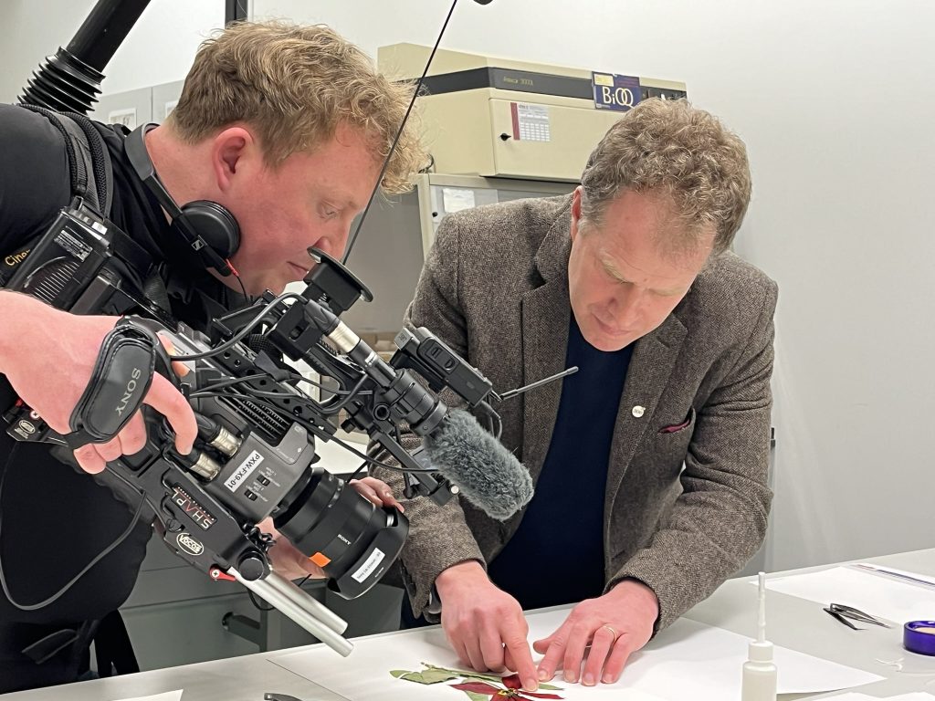 CUBG Curator, Sam Brockington showing a Herbarium specimen on camera