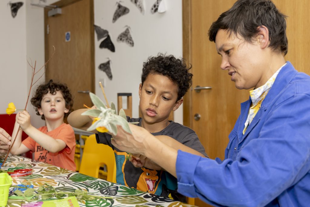 Children create nature wands with parental support.