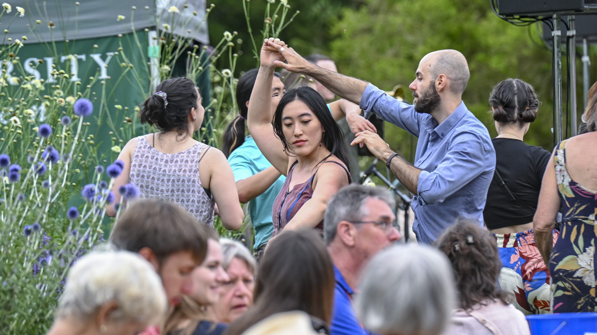 A couple dance amongst a crowd of people enjoying music in the Garden.